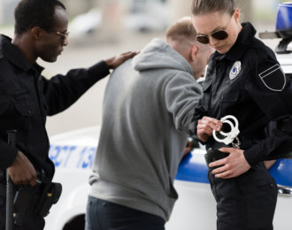 police officers arresting male bandit near car